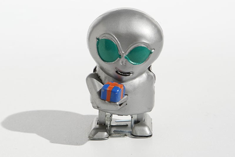 Metallic alien tin toy holding a small gift box