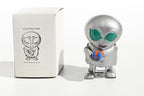 Metallic alien tin toy holding a small gift box with packaging