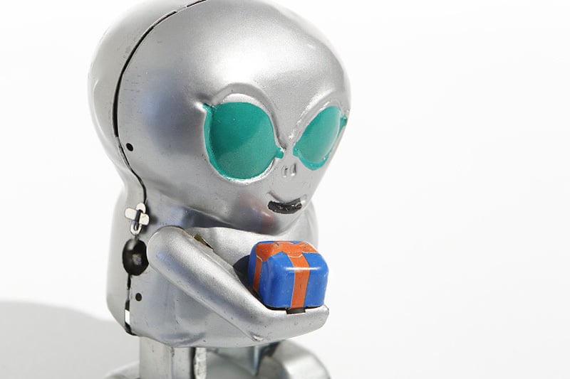 Close up of Metallic alien tin toy holding a small gift box