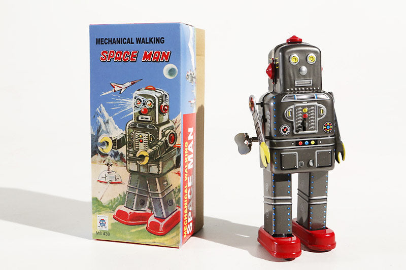 Space Man Vintage-style mechanical walking robot tin toy next to its packaging box 