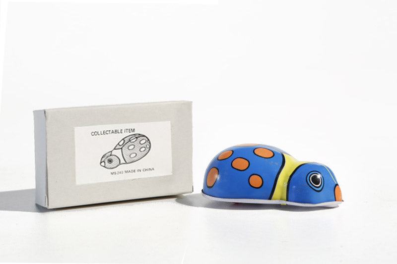 Colourful little bug tin toy with its packaging 