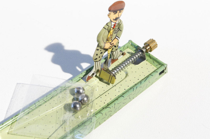 Close up of Little golfer tin toy with golfer and balls