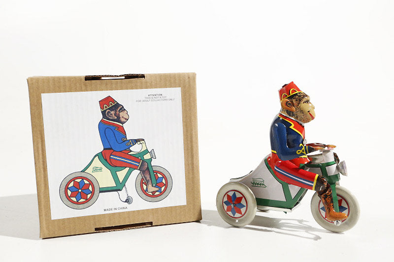 Monkey of tricycle tin toy  next to its packaging