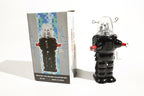 Black robot space trooper tin toy with clear dome and red accents next to its packaging 